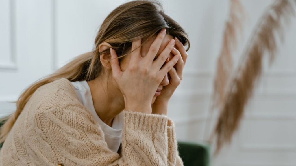 Woman sitting with hand covering her face